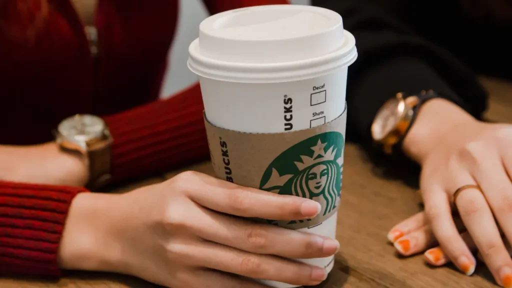 Person Holding A Starbucks Cups on A Table - Is Starbucks Open on Labor Day?