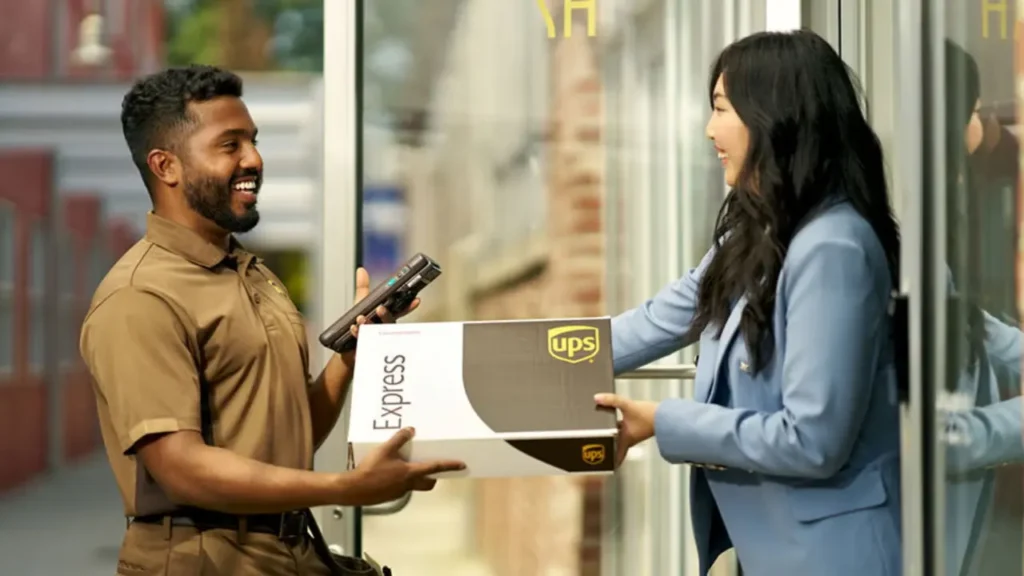 A Smiling UPS Delivery Man Hands a UPS Express Package to A Smiling Woman - Is UPS Store Open on Thanksgiving?